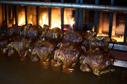 Rotisserie chickens roasting over hickory coals